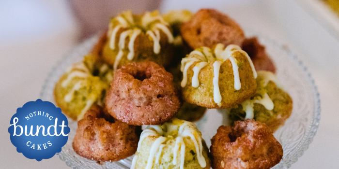 Mini bundt cakes, some with drizzled icing, arranged in a small stack on a glass plate.